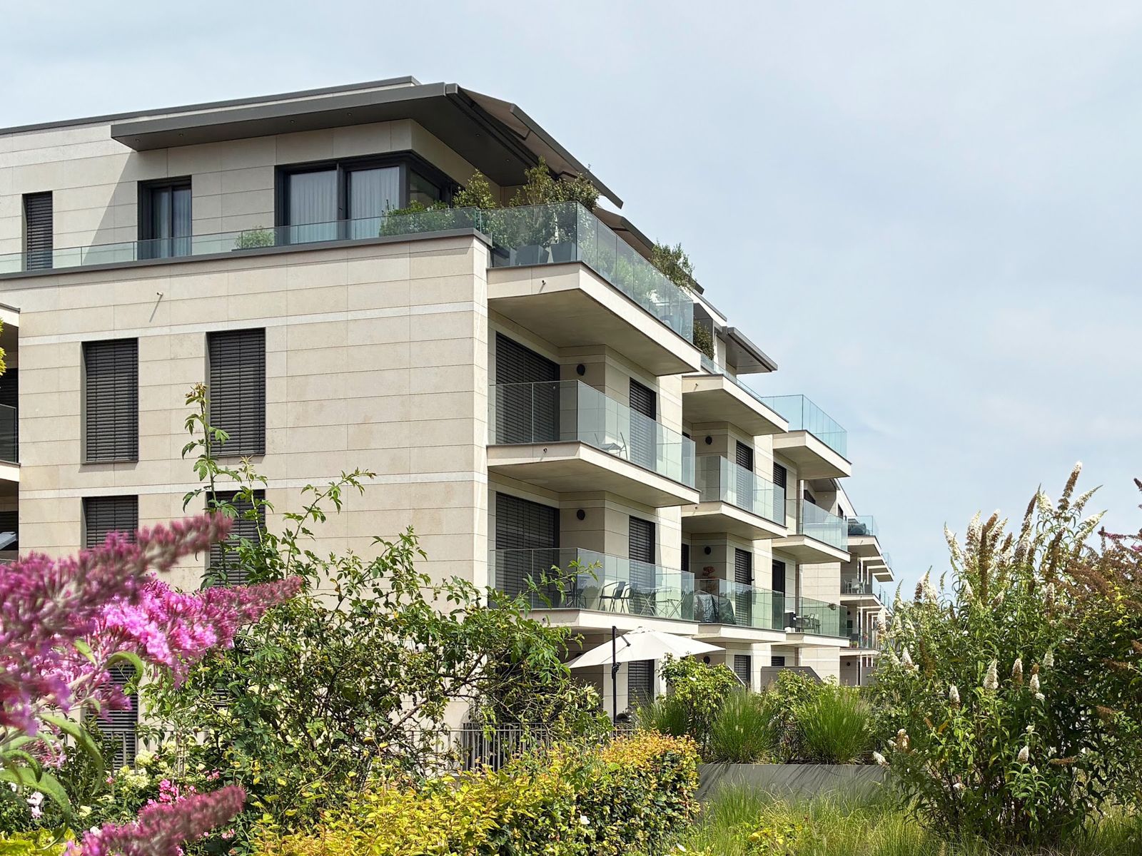 Light stone apartment building behind flowering gardens